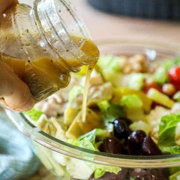 Pouring Homemade Greek Dressing Recipe on Salad